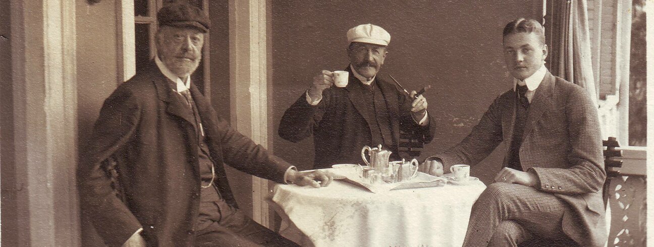 Historická fotografie tří mužů sedících u stolu při odpoledním čaji. | © Archiv SZ Vizovice